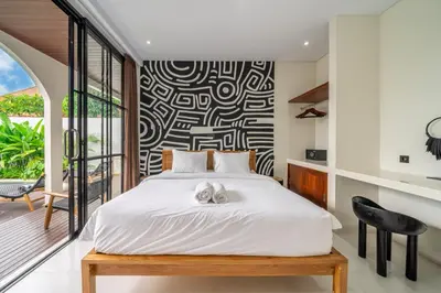 a bedroom with a white bed with a black and white patterned wall at Alisa 4 - Luxurious 4BR Villa with Garden Views and Pool in Seminyak