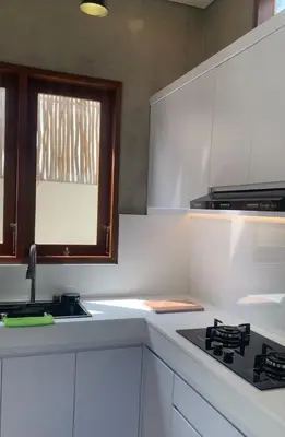 a kitchen with white cabinets and a stove and a window at Wakajima House kuta Utara in Kerobokan