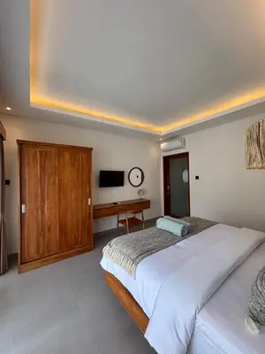a bedroom with a large bed and a desk at Villa Taoro Jimbaran in Jimbaran