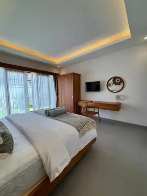 a bedroom with a bed and a desk and a television at Villa Taoro Jimbaran in Jimbaran