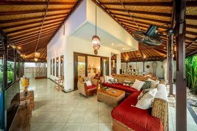 an outdoor living room with a red couch and chairs at Villa Panda Seminyak next to KU DE TA Beach Club in Seminyak