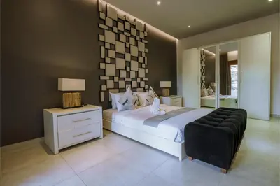 a bedroom with a large bed and a black chair at Villa Orange 2BR Seminyak by Exotic Bali Properties in Badung