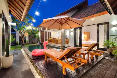 an outdoor patio with an umbrella and a pool at Villa O'Anne II in Seminyak