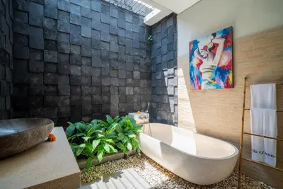 a bathroom with a tub and a painting on the wall at Villa O'Anne II in Seminyak