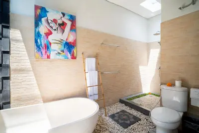 a bathroom with a toilet and a painting on the wall at Villa O'Anne II in Seminyak