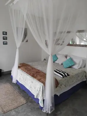 a bedroom with a bed with white curtains at Jimbaran room 01 in Jimbaran