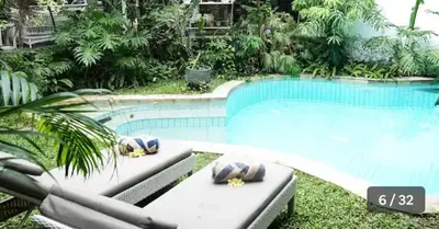 a swimming pool with chaise lounges in front of a swimming pool at Jimbaran room 01 in Jimbaran
