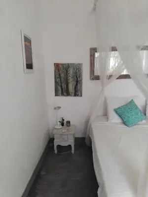 a white bedroom with a bed and a table at Jimbaran room 01 in Jimbaran