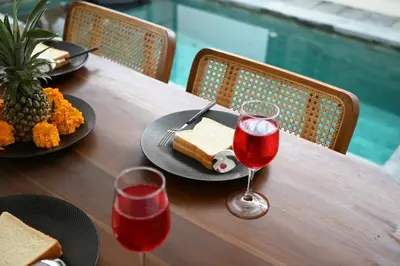 a wooden table with two glasses of red wine and cheese at Villa Bella Wilson III in Seminyak
