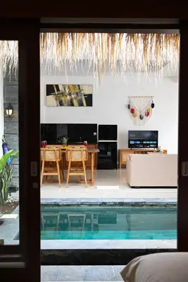 a living room with a swimming pool next to a house at Villa Bella Wilson III in Seminyak