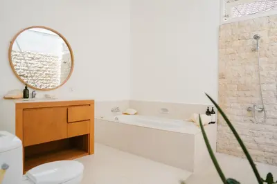 a bathroom with a tub and a toilet and a mirror at Villa Kubu Lebak 3 in Seminyak