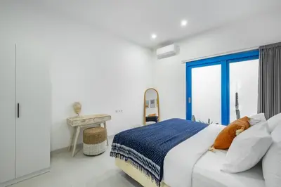 a white bedroom with a bed and a window at Casa Posa Seminyak in Seminyak