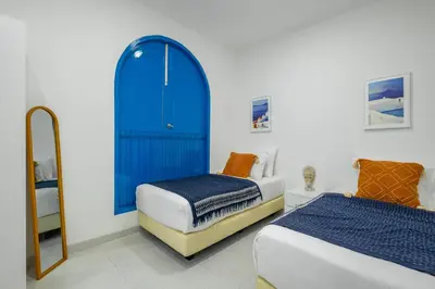 a bedroom with two beds and a blue door at Casa Posa Seminyak in Seminyak