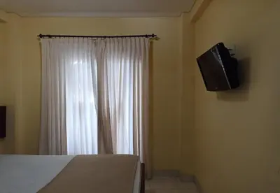 a bedroom with a bed and a television on the wall at Hotel Damai in Denpasar