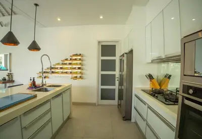a kitchen with white cabinets and a wine rack at Bali Modern Escape With Private Pool, 8 guests in Kerobokan