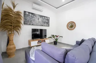 a living room with a purple couch and a tv at Aster Villa by iBali Management in Legian