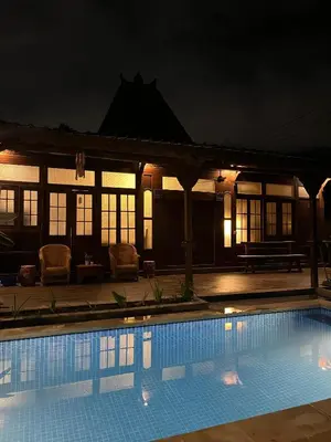a swimming pool in front of a house at night at Oemah Djoglo Kerobokan in Kerobokan