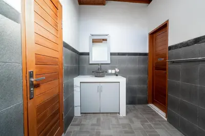 a bathroom with a sink and a mirror next to a door at 3 Bedroom Villa Mawar walk to Beach Legian in Legian