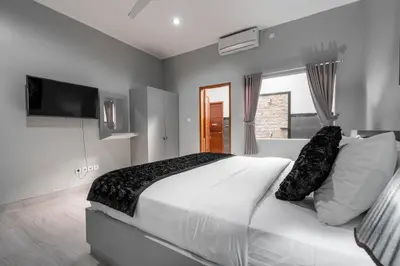 a bedroom with a large white bed and a flat screen tv at 3 Bedroom Villa Mawar walk to Beach Legian in Legian