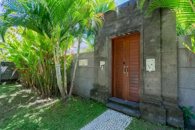 a building with a wooden door next to a palm tree at 3 Bedroom Villa Mawar walk to Beach Legian in Legian