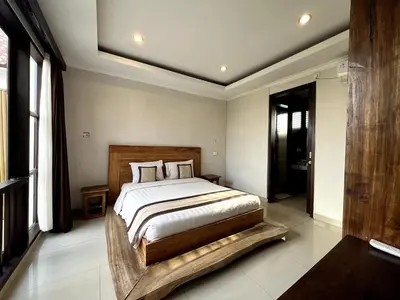 a bedroom with a large bed with a wooden headboard at White Lotus Villa by Miel Property in Seminyak