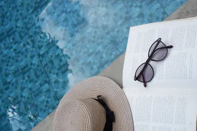 a hat and glasses sitting next to a swimming pool at VILLA BELLA - 7Min Beach Access - 10min to Canggu in Canggu