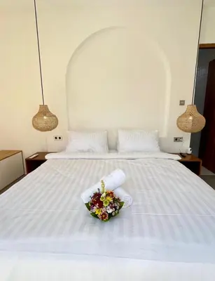 a white bed with a bowl of flowers on it at Villa Boginville in Kerobokan
