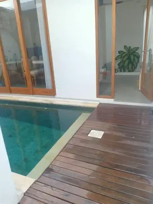 a swimming pool in a house with a wooden deck at Villa Boginville in Kerobokan