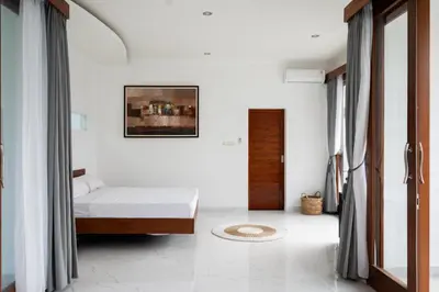 a bedroom with a bed and a door with curtains at Villa Manis with a private pool in Nusa Dua in Nusa Dua