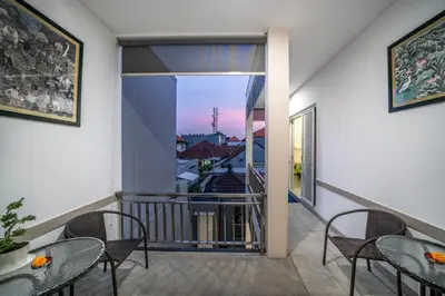 a balcony with tables and chairs and a view of a city at KUTA - 3 Bedroom Private Pool Villa on Jl Mataram! in Kuta