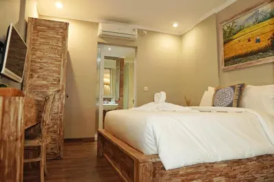 a bedroom with a large white bed and a bathroom at Koura Jimbaran in Badung