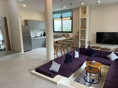 a living room with a purple couch and a kitchen at Cozy 3 Bedrooms Villa Umalas in Kerobokan