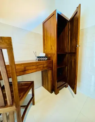a wooden desk with a chair and a cabinet at Nyoman19 Guest House in Seminyak