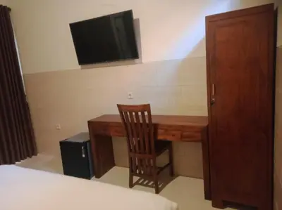 a desk with a chair and a television on a wall at Nyoman19 Guest House in Seminyak