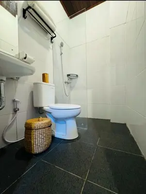 a bathroom with a toilet and a sink and a basket at Nyoman19 Guest House in Seminyak