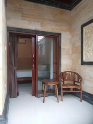 a chair and a table in a room at Nyoman19 Guest House in Seminyak