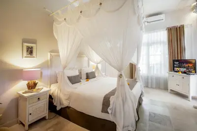 a bedroom with a canopy bed with white curtains at Villa Lodek Deluxe in Seminyak