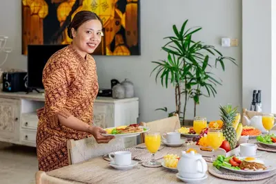 a woman standing at a table with a plate of food at Villa Lodek Deluxe in Seminyak