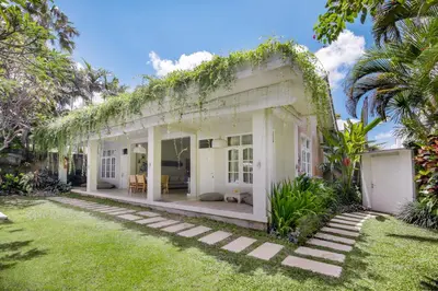 an exterior view of a white house with a yard at Villa Lodek Deluxe in Seminyak