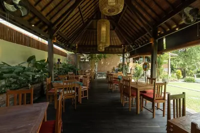 an empty restaurant with wooden tables and chairs at Natajiwa Village close to Canggu and Seminyak in Seminyak