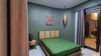 a bedroom with a green bed in a room at The Kutata in Jimbaran