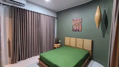 a bedroom with a green bed and a window at The Kutata in Jimbaran