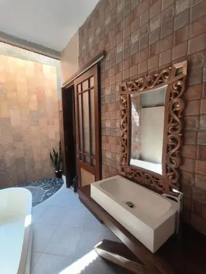 a bathroom with a sink and a mirror at The Kutata in Jimbaran
