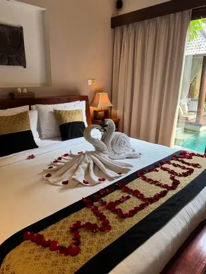 two swans are sitting on a bed with red rose pedals at Villa Green Manggo Seminyak Bali in Seminyak