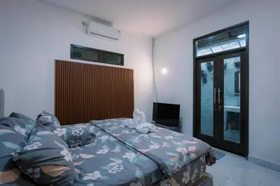 a bedroom with a bed and a tv and a window at Hawaiian Beach House in Legian