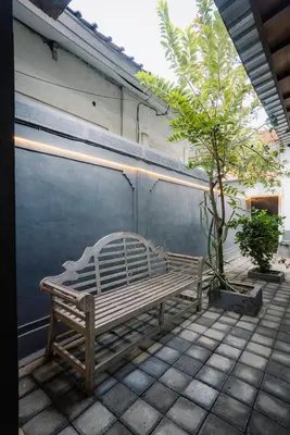 a wooden bench sitting on a patio next to a tree at Hawaiian Beach House in Legian