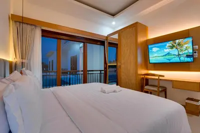 a bedroom with a white bed and a television at Villa Boswellia Seminyak near Double Six Beach in Seminyak