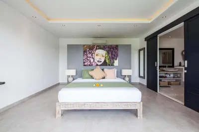 a bedroom with a bed with a painting on the wall at Villa Elisa in Canggu