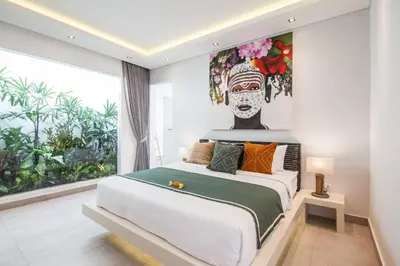 a bedroom with a large bed with a painting on the wall at Villa Elisa in Canggu