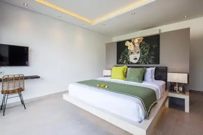 a bedroom with a bed with a painting on the wall at Villa Elisa in Canggu